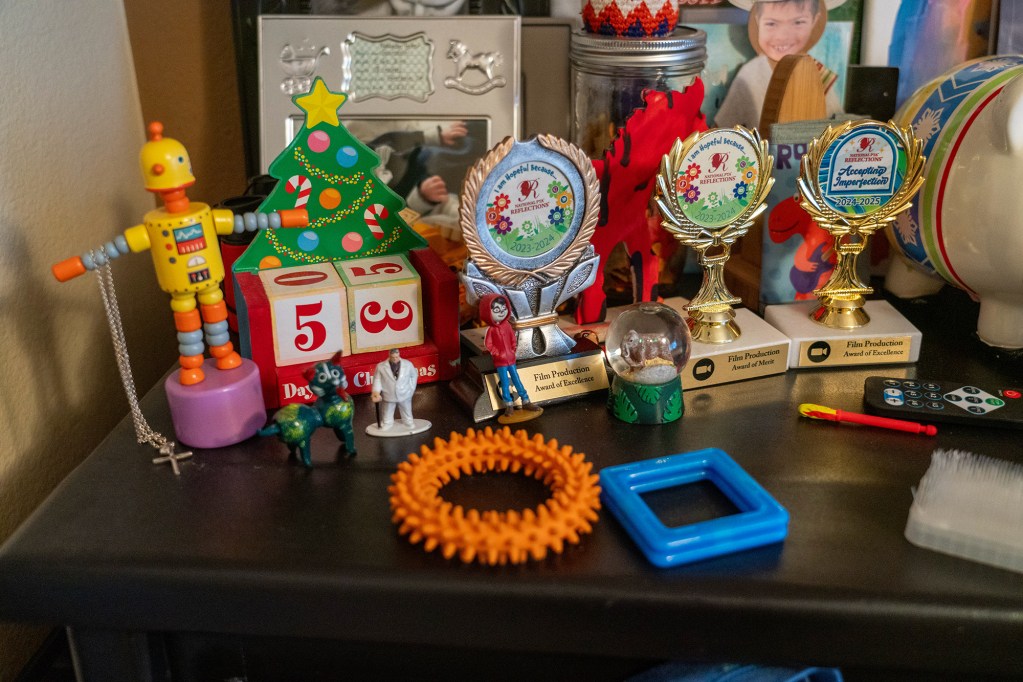 Awards, toys and stimulation devices sit on top of a brown dresser.